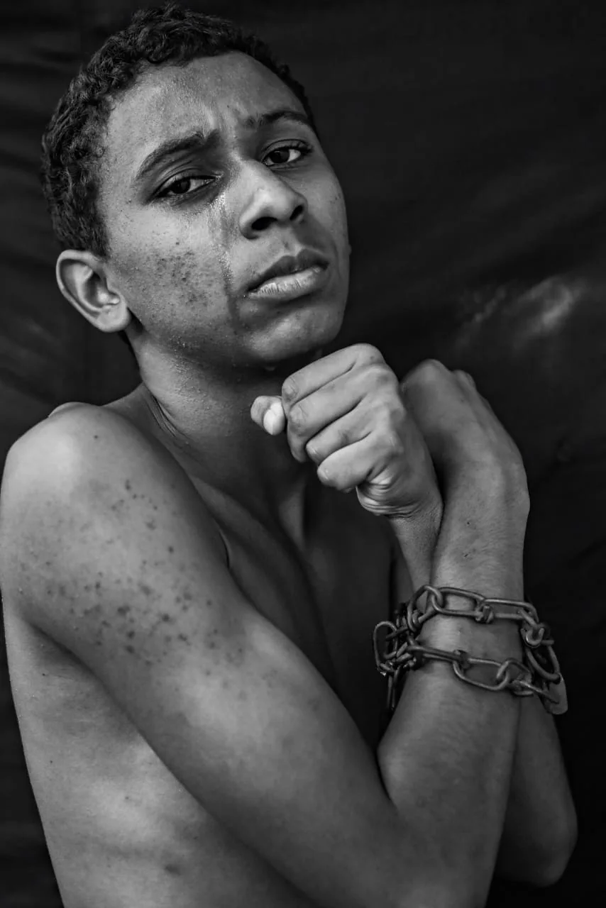Jovem chora e mantém os punhos próximos ao rosto em retrato de dor e resistência